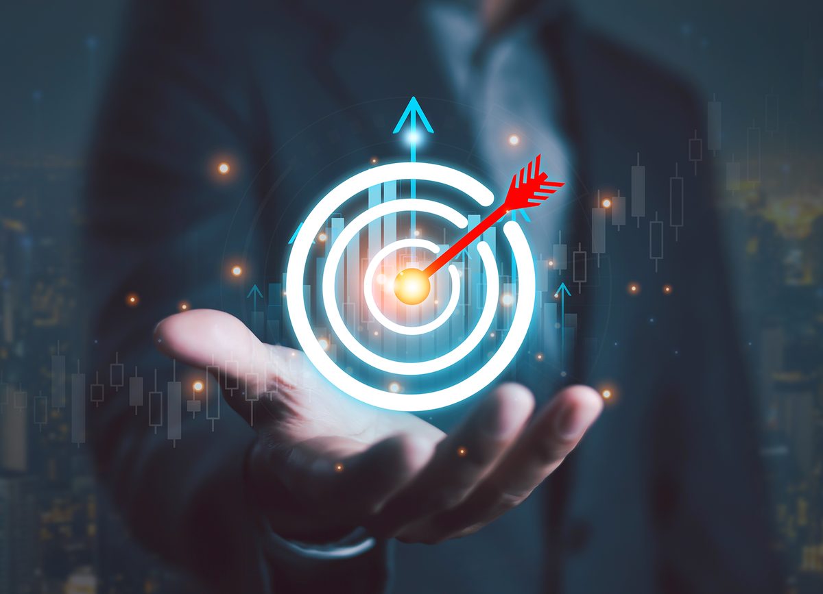 An open hand holding a glowing target with an arrow in the bullseye